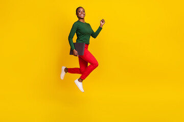 Wall Mural - Full length photo of cute adorable woman wear green shirt holding device jumping empty space isolated yellow color background