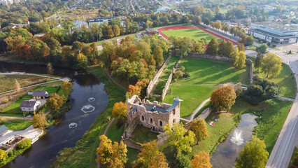 Wall Mural - Ruins of an Ancient Medieval Castle Dobele Latvia, Aerial Top View. Aerial Panorama of Dobele City, in the Foreground River With Fontains and Medieval Castle Ruins With Restored Castle Capella, Latvia