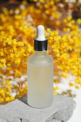 Wall Mural - Transparent frosted glass dropper bottle with serum, tonic or essential oil on grey concrete podium with yellow flowers. Soothing cbd oil. Alternative Medicine. Beauty concept for face and body care