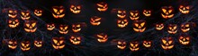Scary Halloween Celebration Holiday Card - Many Spooky Carved Pumpkins And Spider Web On Dark Wooden Wall Background Banner Panorama.