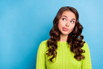 Sticker - Photo of lovely young lady curly hairdo uncertain look empty space wear trendy fall green knitted jumper isolated on blue color background