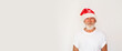 Portrait of a mature grey-bearded man wearing a white t-shirt and Santa hat, on a white studio background