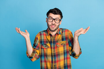 Sticker - Photo of handsome young confused guy in eyewear dressed plaid shirt question shrugging shoulders isolated on blue color background