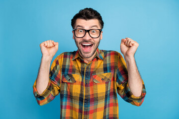 Canvas Print - Photo of impressed astonished ecstatic man wear glasses plaid shirt hold hands up screaming yes isolated on blue color background