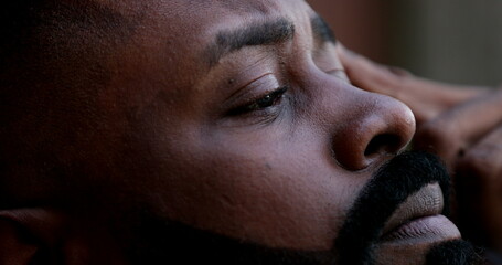 Wall Mural - Pensive worried black African man close-up eyes looking up to sky seeking God help