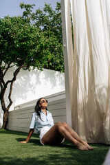 Wall Mural - Portrait of young beautiful woman in tropical destination park with greenery on the background. Joy of summer holidays concept.