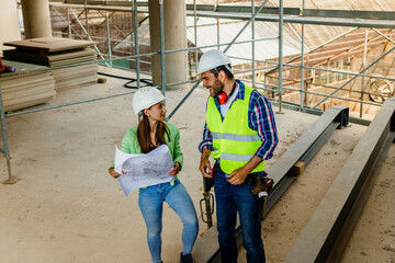 Two happy civil engineer and maintenance engineer in protective vests and helmets working on a construction site