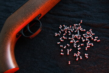 Rifle gun trigger with air pellets for hunting on cloth dark background with red light