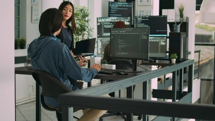 Asian database developers analyzing compiling code on multiple screens, working on new app interface development. System engineers using terminal window with firewall server data.
