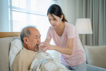 Female caregiver giving senior man medical pills,Medical assistance for elderly people,Routine health check and giving medication.