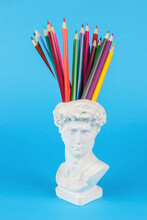 Plaster Statuette With Pencils In The Head On A Blue Background. Minimal Concept.