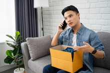 Unhappy Asian man client or buyer talk with customer service on cellphone. He is frustrated by delivery mistake or error