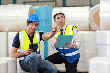 Architect or engineering men and worker sitting and checking large warehouse with tablet and clipboard. Multiethnic two business manager pointing and looking in future with warehouse building.