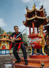 Man Holding A Sword Standing In Wushu Position Near Gold Dragon Statue