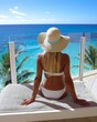 © Scopio - Woman in white bikini wearing white sun hat sitting on white towel near swimming pool