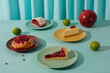 © TrueFrame Collective - Horizontal high angle still life studio shot of sweet cakes, pies, limes and pomegranate against blue background