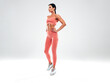 © halayalex - Tanned fitness woman in pink sports clothing. Sexy young beautiful model with perfect body.Female isolated on grey background in studio. Stretching out before training