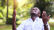 © arrowsmith2 - African man in white shirt praying for thank god in the green nature background