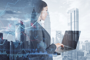 Poster - businesswoman using laptop with creative forex chart with candlestick graph, index and tech hologram on blurry white daylight toning city background. 