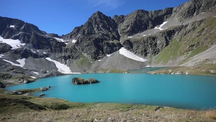 Wall Mural - Beautiful landscape of a lake in the Caucasus before the morning of a sunny day in early autumn. Sparkling turquoise blue water. Mountain peaks in the background. Caucasus. Russia