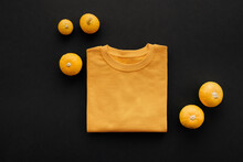 Top-down View Shot Of Modern Halloween Flat Lay Composition With Small Pumpkins And T-shirt On Dark Gray Surface