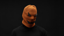 Horizontal Close-up Studio Portrait Of Modern Unrecognizable Man Wearing Black Outfit With Jack O Lantern Mask Made Out Of Orange Knit Cap And Paper