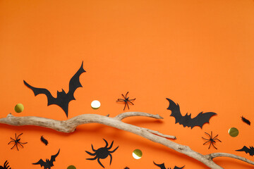 Wall Mural - Flat lay composition with paper bats, spiders and wooden branch on orange background, space for text. Halloween decor