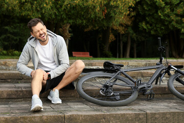 Wall Mural - Man with injured knee on steps near bicycle outdoors