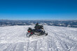 Snowmobile rider on snowy mountains top with blue sky