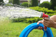 Man spraying water from hose in garden, closeup