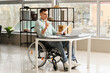 © Pixel-Shot - Young man in wheelchair working in office