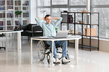 Wall Mural - Young man in wheelchair resting at workplace