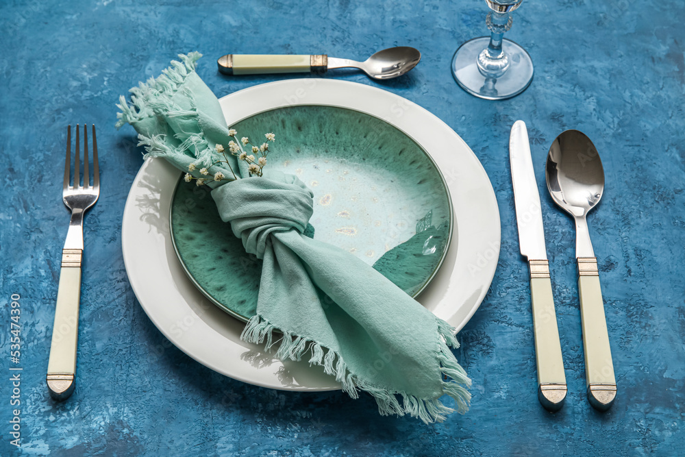 Dinnerware and gypsophila flowers on blue table