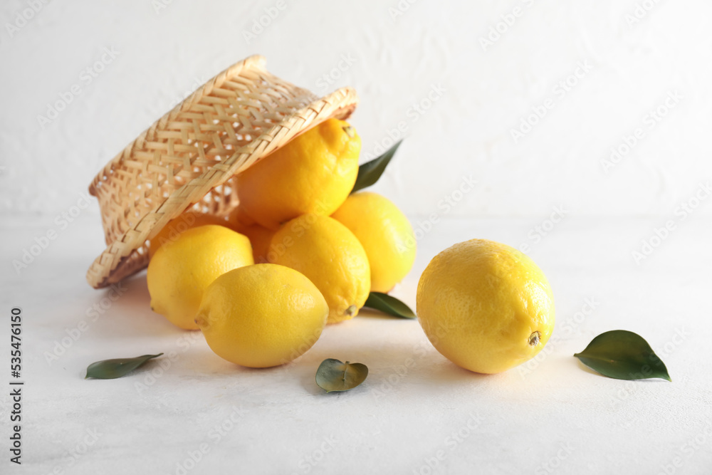 Overturned basket with ripe lemons on light background