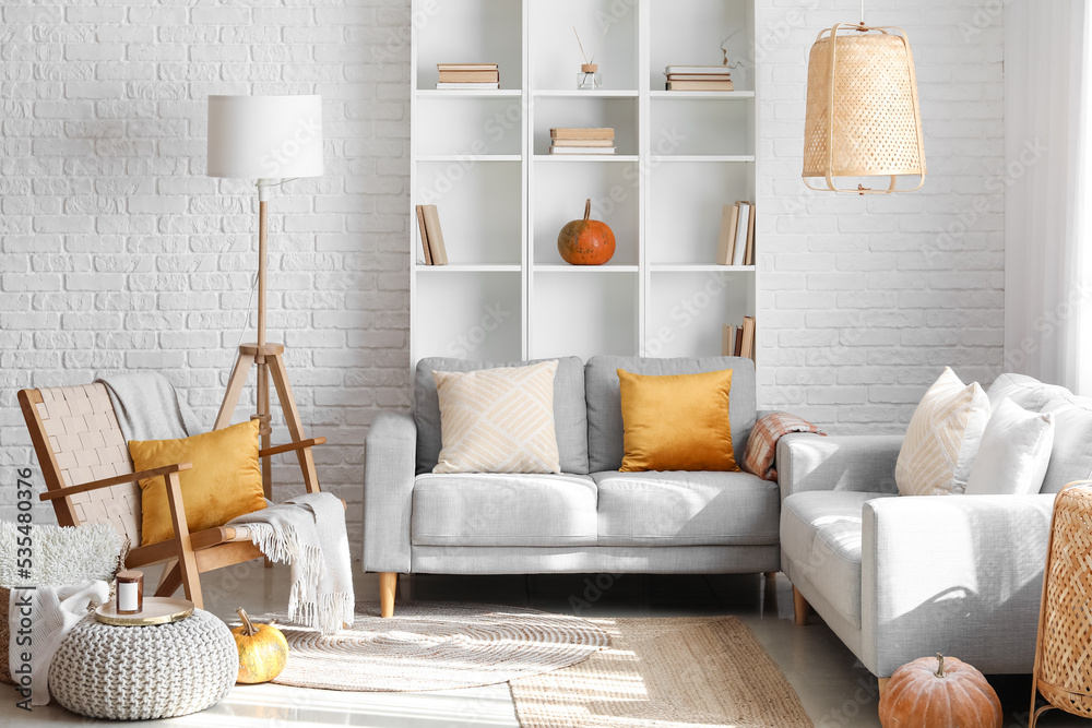 Interior of modern living room with grey sofas, shelving unit and pumpkins