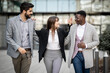 © Panorama - Three succesfull business people talking to each other and smiling other during meeting in the city. Using mobile. Mixed race