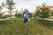 © inna717 - A little girl with long hair jumps having fun on the street. The concept of a happy childhood.