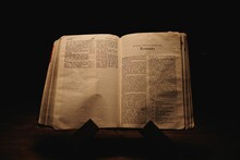 Closeup Shot Of A Historic Old Bible Open On The Romans Pages On Display In A Dark Room