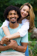 © Solid photos - Young smiling mixed race couple standing and hugging in the nature on a beautiful summer day