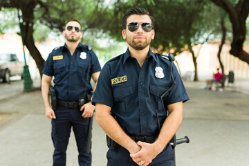 Wall Mural - Caucasian cops on duty standing outdoors in the park