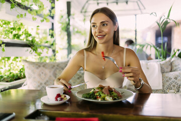 Young woman eating healthy food sitting in the beautiful interior