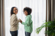 © LIGHTFIELD STUDIOS - curly african american woman smiling while holding hands with cheerful preteen daughter.