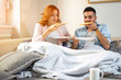 © Bojan - Cute young happy couple eating pizza together covered with blanket on sofa at home.