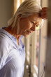 © Wavebreak Media - Thoughtful senior caucasian woman standing in bedroom, looking through window