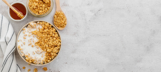 Flat lay (top view) of Crunchy oat granola cereal with fresh milk in bowl and wooden spoon isolated on background.