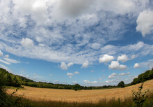 beautiful blue sky with wispy clouds over a field of crops taken with a fisheye lens
