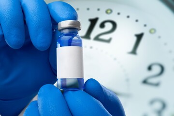 Sticker - Classic medical bottle for vaccine in hands on clock background.