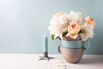 Romentic concept. Tender colorful summer roses and peonies flowers and blue candle against blue background. Selective focus. Still life. Postcard. Place for text. Banner.