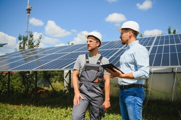 Two engineers are conducting outdoor inspection of solar photovoltaic panels