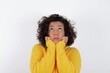 © Roquillo - Portrait of sad young beautiful woman with curly short hair wearing yellow sweater over white background hands face look empty space